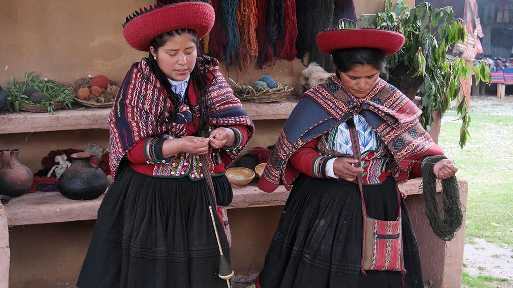 Due donne peruviane vestite tipiche che filano la lana di alpaca