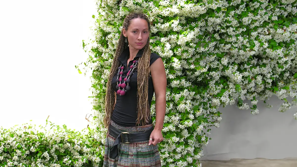 stile bohemien giovane donna con abbigliamento boho hippie, in piedi davanti ad una grande pianta di gelsomino in fiore