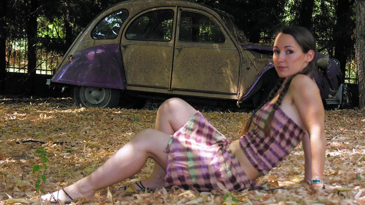 gonna boho chic moda donna ragazza seduta in un prato con gonna corta stile boho, vecchia macchina sullo sfondo