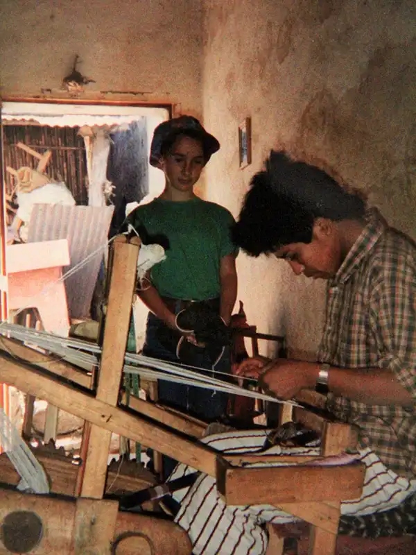 Tessuti etnici in Guatemala, una ragazzina guarda un artigiano che tesse con un telaio manuale