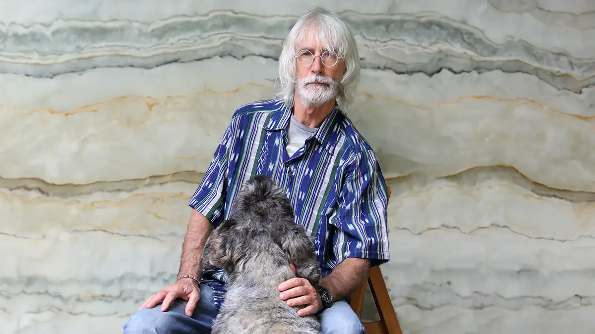 Bohemian style uomo Bohemian style uomo: Uomo con barba e capelli bianchi , seduto che accarezza un cane. L'uomo indossa una camicia blu stile boho