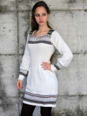 Donna con vestito corto di alpaca bianco, motivo jacquard nero, beige e grigio sul fondo e sulle maniche, modello Giuditta.