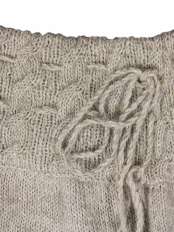 Primo piano della fascia in vita della gonna in alpaca, con lavorazione a trecce, lacci regolabili e nappine finali, modello Angy.
